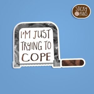 A pun sticker with the phrase 'I'm Just Trying to COPE' written on a coping saw. Sticker is on a blue background with a sticky puns logo in the top right corner.