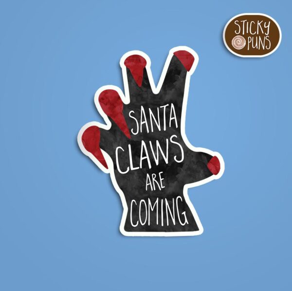 A pun sticker with the phrase 'Santa CLAWS Are Coming' written on a black hand with long red fingernails.  Sticker is on a blue background with a sticky puns logo in the top right corner.