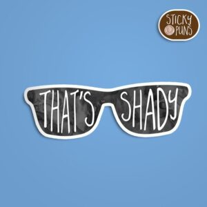 A pun sticker with the phrase 'That's shady' written on a pair of sunglasses. Sticker is on a blue background with a sticky puns logo in the top right corner.
