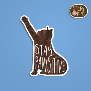 A pun sticker with the phrase 'Stay PAWsitive' featuring a cute cat. Sticker is on a blue background with a sticky puns logo in the top right corner.