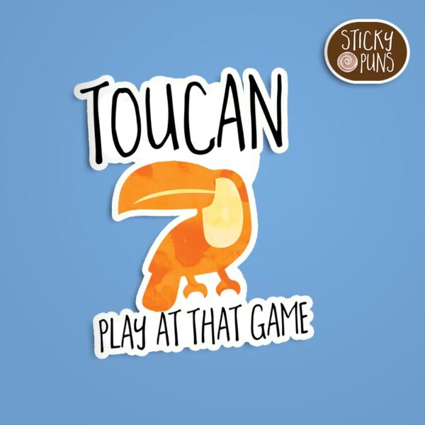 A pun sticker with the phrase 'TOUCAN play at that game' featuring a toucan. Sticker is on a blue background with a sticky puns logo in the top right corner.