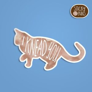 A pun sticker with the phrase 'I knead you' featuring a cat. Sticker is on a blue background with a sticky puns logo in the top right corner.