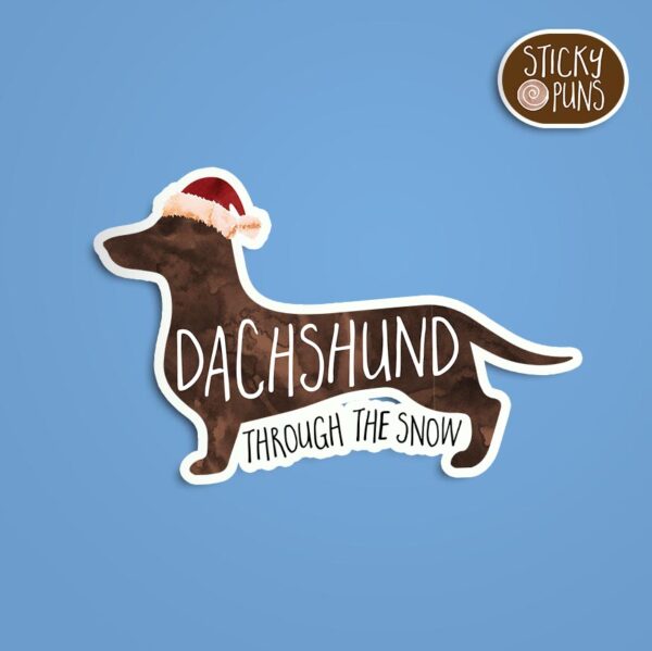 A pun sticker with the phrase 'Dachshund through the snow.'  Sticker is on a blue background with a sticky puns logo in the top right corner.