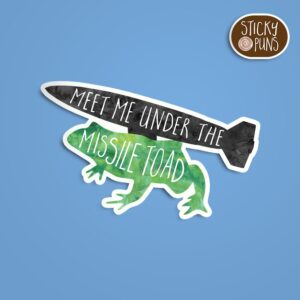 A pun sticker featuring a frog with a missile on its back and the phrase 'Meet me under the missile toad.' Sticker is on a blue background with a sticky puns logo in the top right corner.