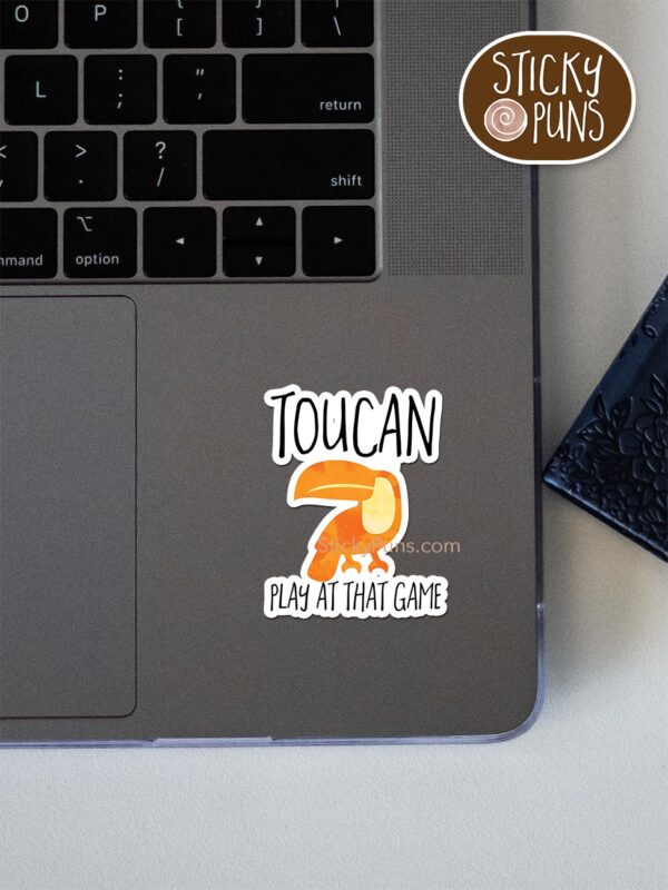 TOUCAN play at that game pun sticker shown stuck on a laptop