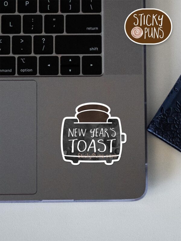 New Year's TOAST pun sticker shown stuck on a laptop