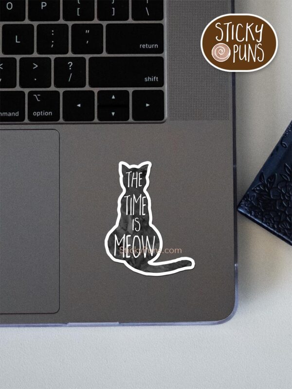 The time is MEOW - cute cat pun sticker shown stuck on a laptop