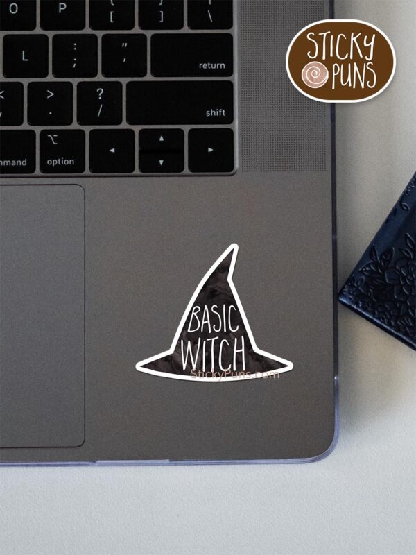 Basic witch pun sticker shown stuck on a laptop