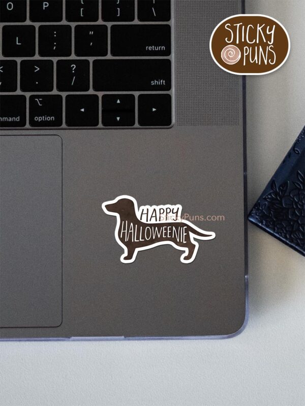 Happy HalloWEENIE pun sticker shown stuck on a laptop