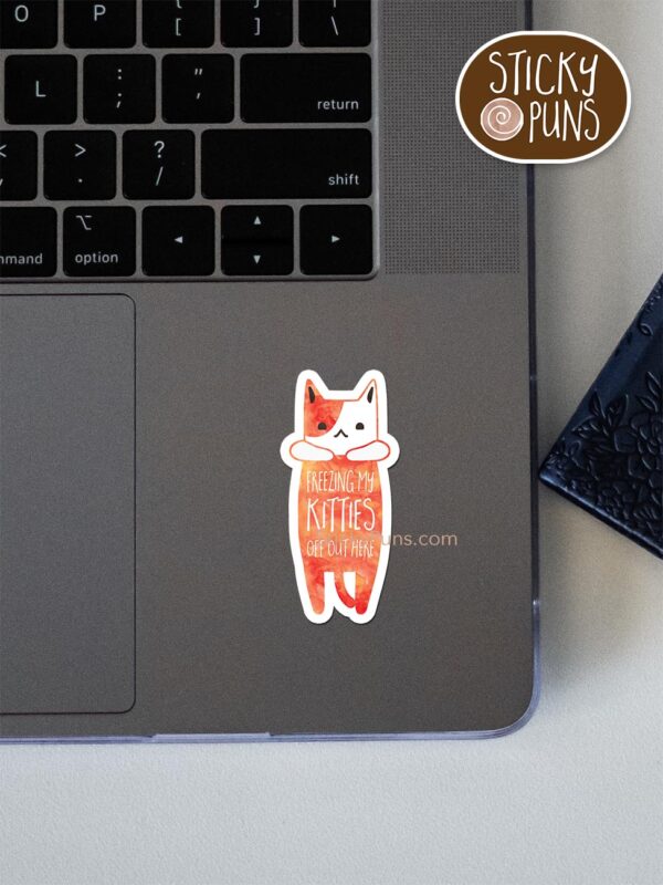 freezing my kitties off pun sticker shown stuck on a laptop