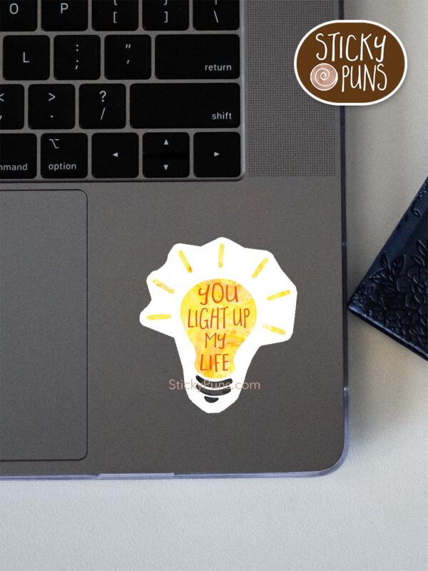 you light up my life pun sticker shown stuck on a laptop