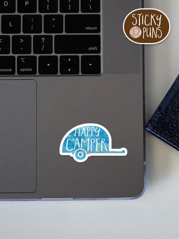 happy camper pun sticker shown stuck on a laptop