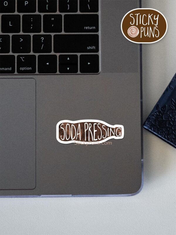 soda pressing pun sticker shown stuck on a laptop